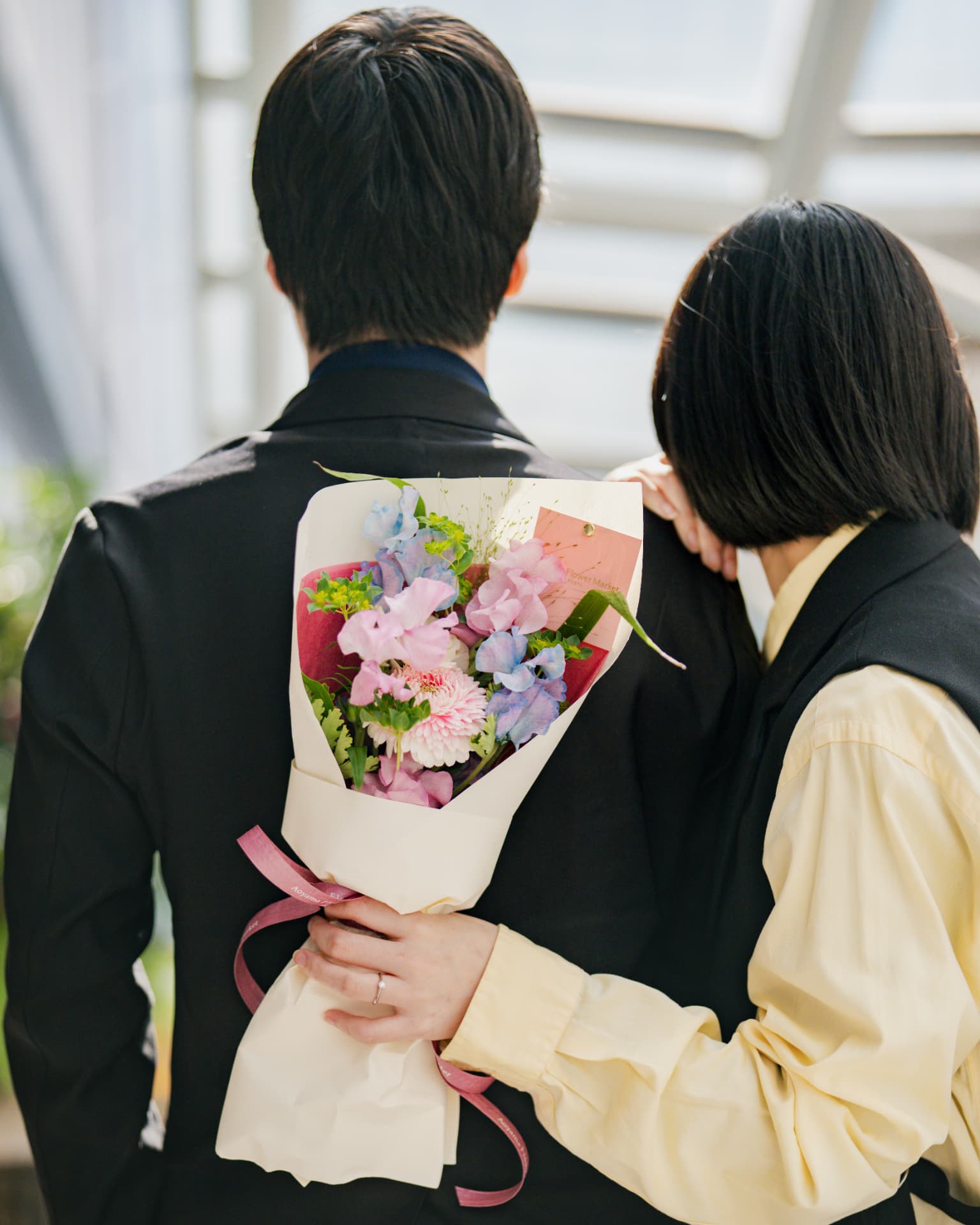 花束を手に寄り添うふたりの後ろ姿