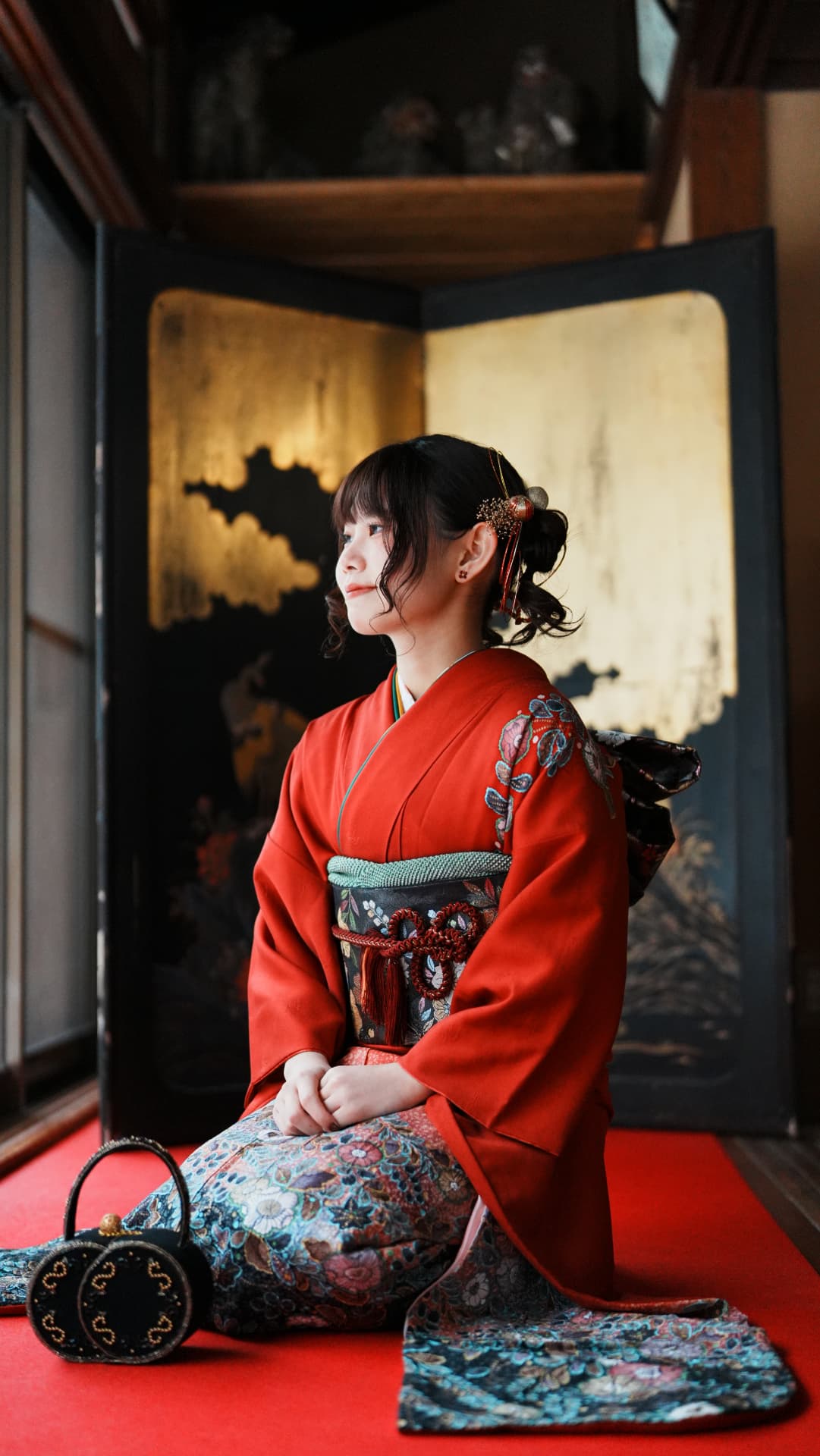 金屏風の前に座る振袖姿の女性